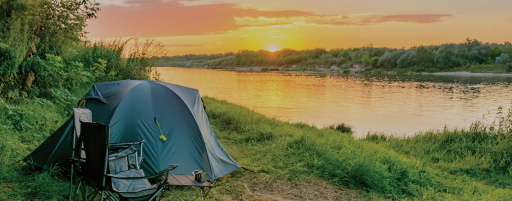 A tent set up by a lake at sunset